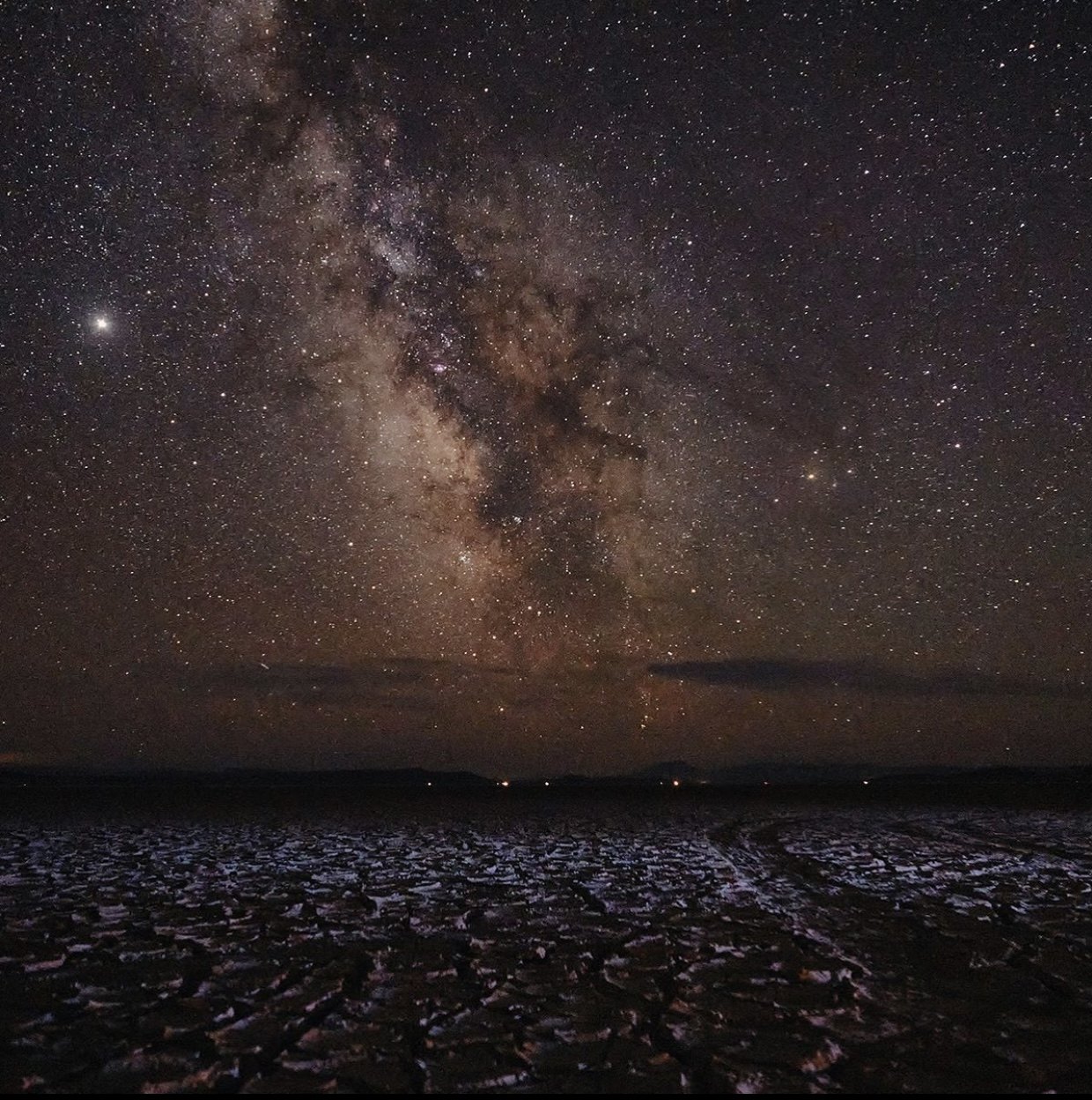 The Milky Way rising over a cracked desert floor at night.